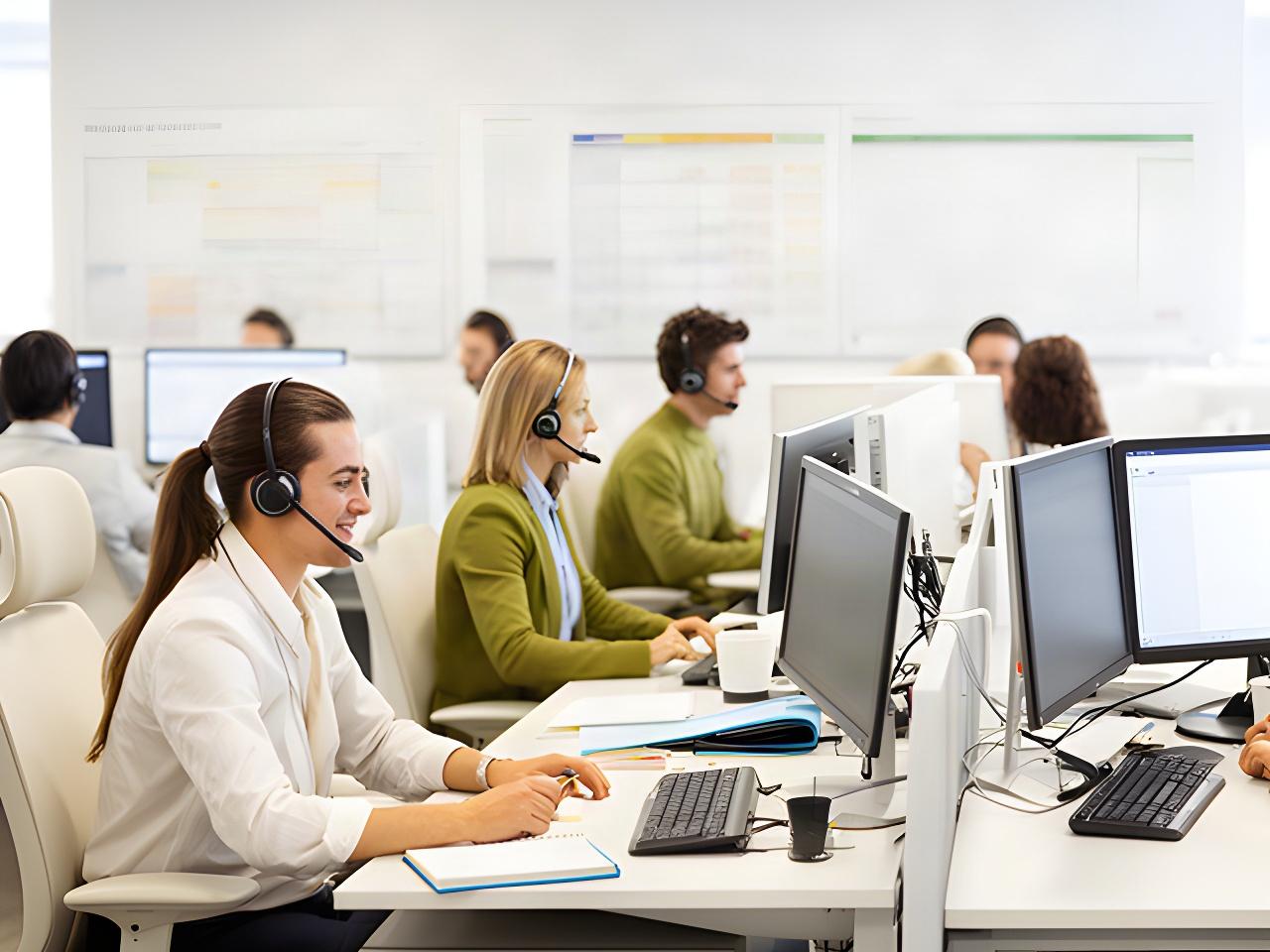Operations team working at desks in a bright customer contact centre with headsets and schedules